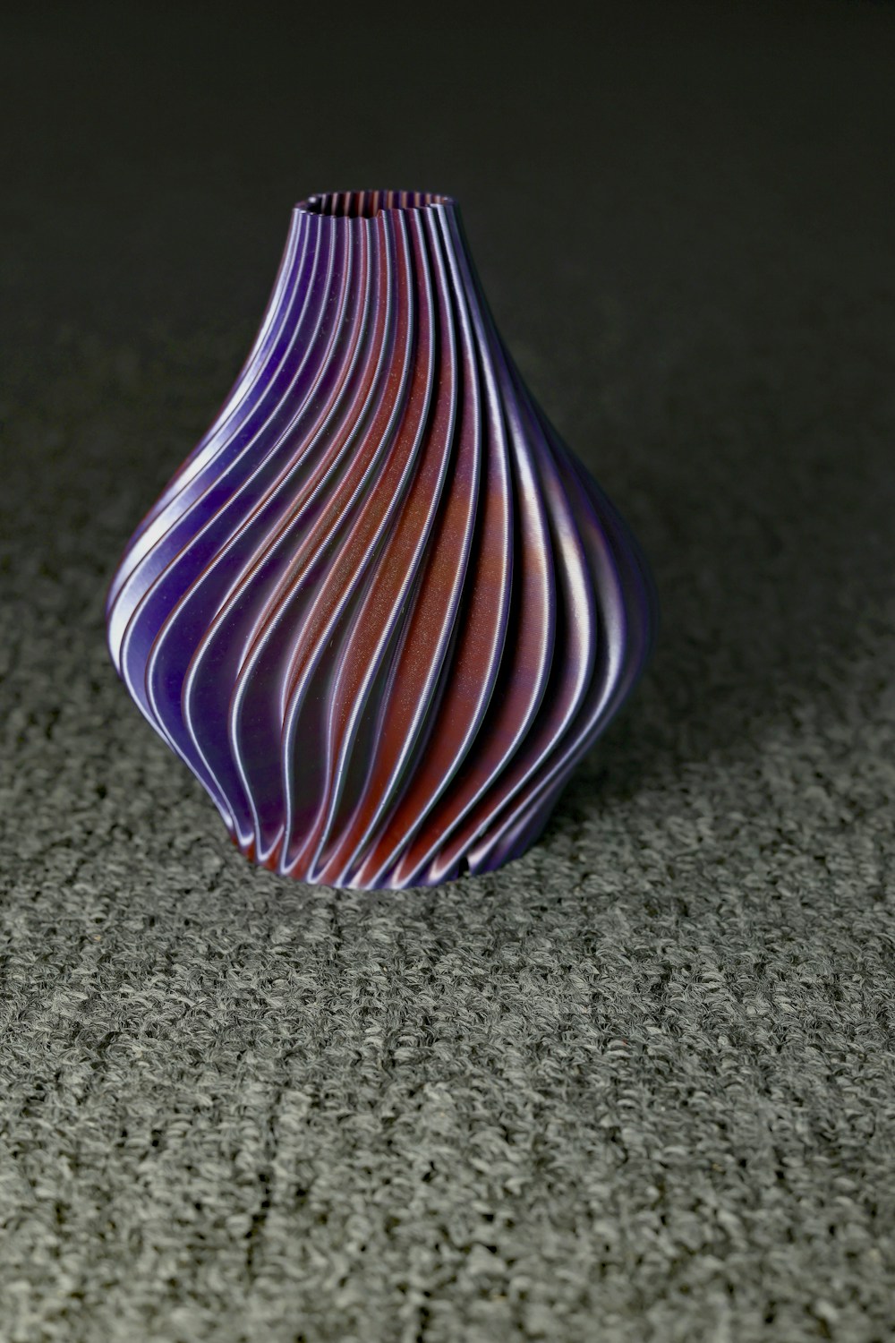 A purple 3D printed vase with sculpted, rippled sides