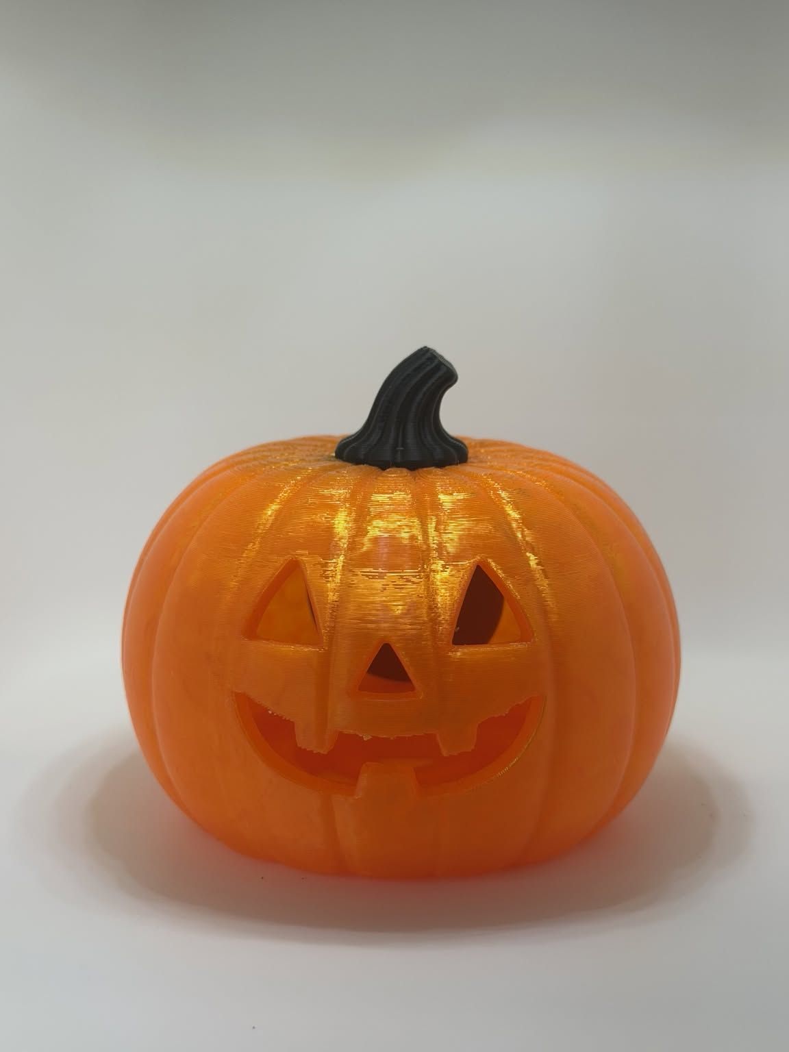 Orange jack-o&rsquo;-lantern with a carved face and a dark stem