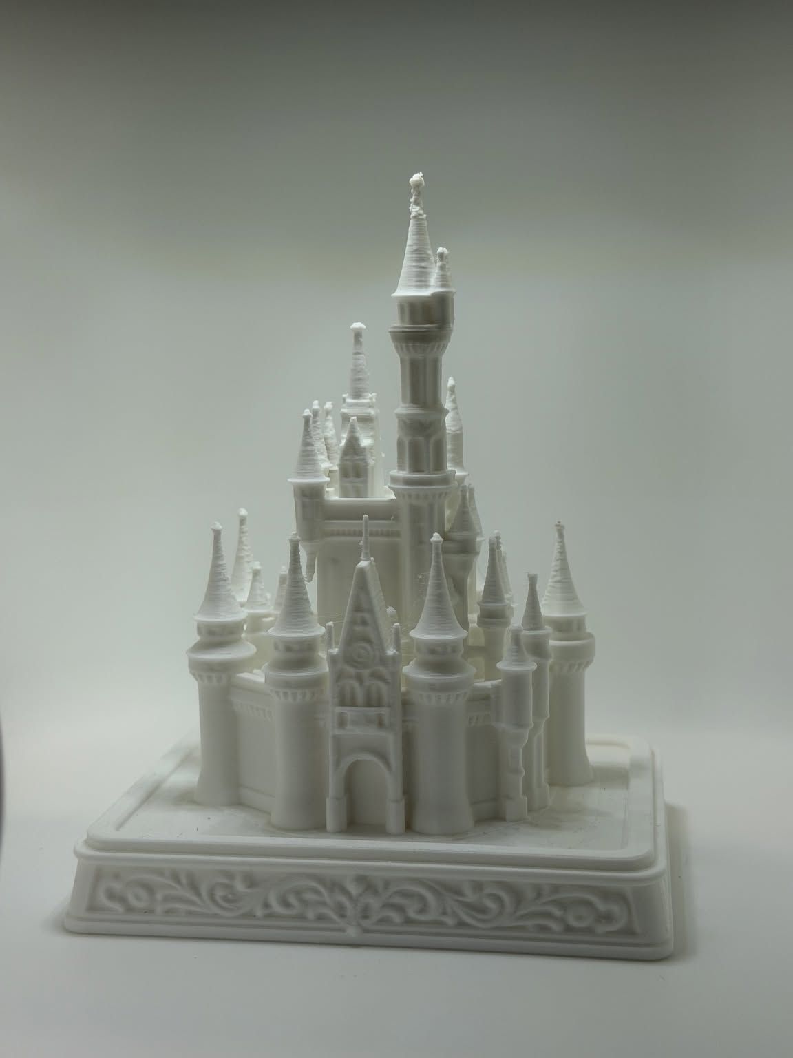 White castle with many tall spires standing on a decorative base